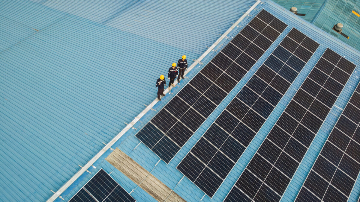 solar roof, fotovoltaika, paneli, Aerial view of engineer worker walking on rooftop checking on solar cell panels installed on roof of the factory with professional team. Electric power industry renewable energy.