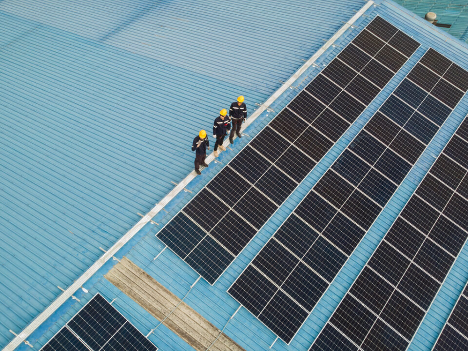 solar roof, fotovoltaika, paneli, Aerial view of engineer worker walking on rooftop checking on solar cell panels installed on roof of the factory with professional team. Electric power industry renewable energy.